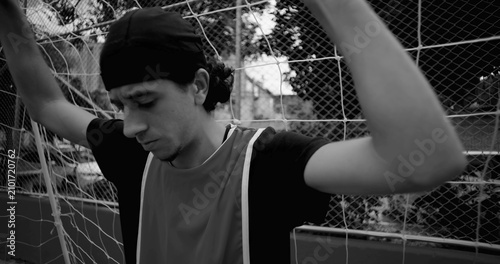 Photography Hispanic soccer player leans against goal net in quiet reflection after game, lo