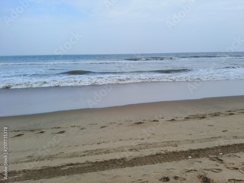 фотографія Rolling surf on a sandy beach featuring deep tire impressions seascape landscape