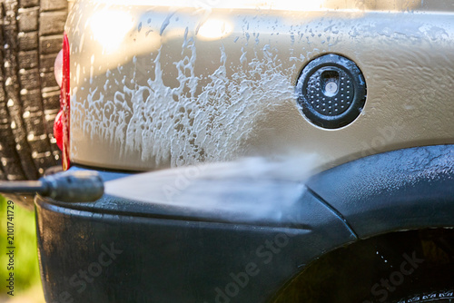 Obraz na płótnie Close-up of car being washed with high-pressure hose and soap suds