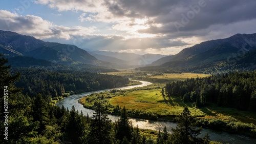 Magnificent mountain valley with winding river under dramatic sunlight ideal for travel advertising nature background and tourism marketing