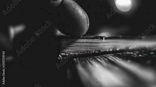 Close up monochrome image of a finger touching stacked papers with selective focus