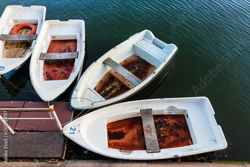 Fotografija White rowboats at a pier on the water after rain