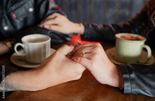 Fotografía Pareja tomada de las manos durante una cita romántica en una cafetería con tazas