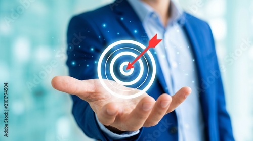 Strategic business target hologram with a red arrow hitting the center, held by a professional in a suit for corporate growth