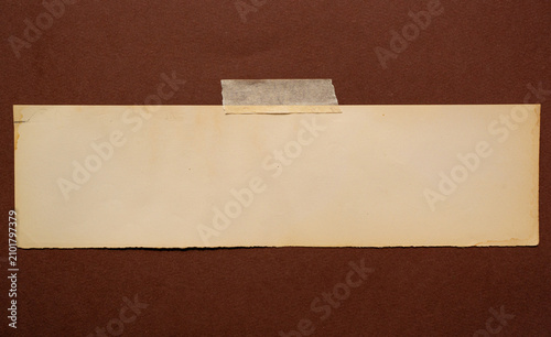Papel antiguo color crema pegado con cinta adhesiva sobre fondo marrón, espacio para texto
