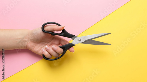 Hand cutting paper with black scissors on colorful background