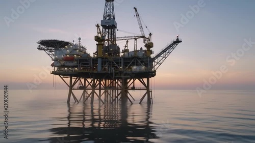 Offshore oil platform stands in the middle of the ocean during sunset. Industrial drilling structure for energy extraction at sea. Power production facility plant