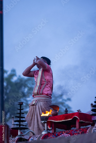 Ganga aarti, Portrait of the young unidentified male priest performing holy river ganga early morning aarti at assi ghat in traditional dress with hindu rituals.
