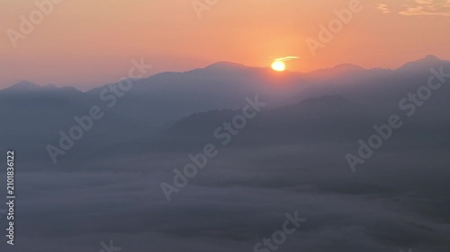 Sunrise glows over distant mountains. Warm orange light illuminates the scene at Lenggong, Malaysia