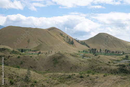 Scenic Landscape of Rolling Hills Under a Bright Sky with Vivid Greenery and Soft Clouds