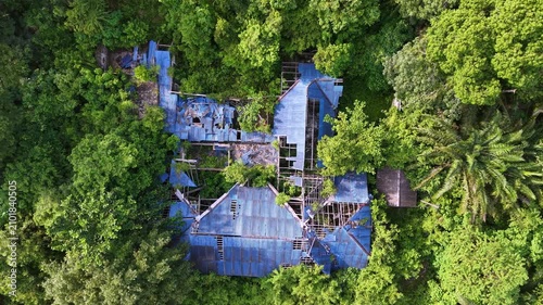 Aerial view captures a dilapidated building with blue corrugated roofs