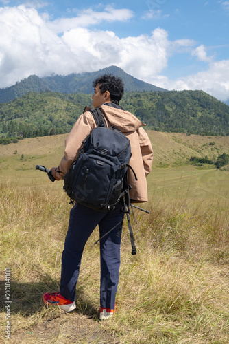 A Solo Adventurer Standing Against a Majestic Mountain Landscape Beneath a Bright Blue Sky