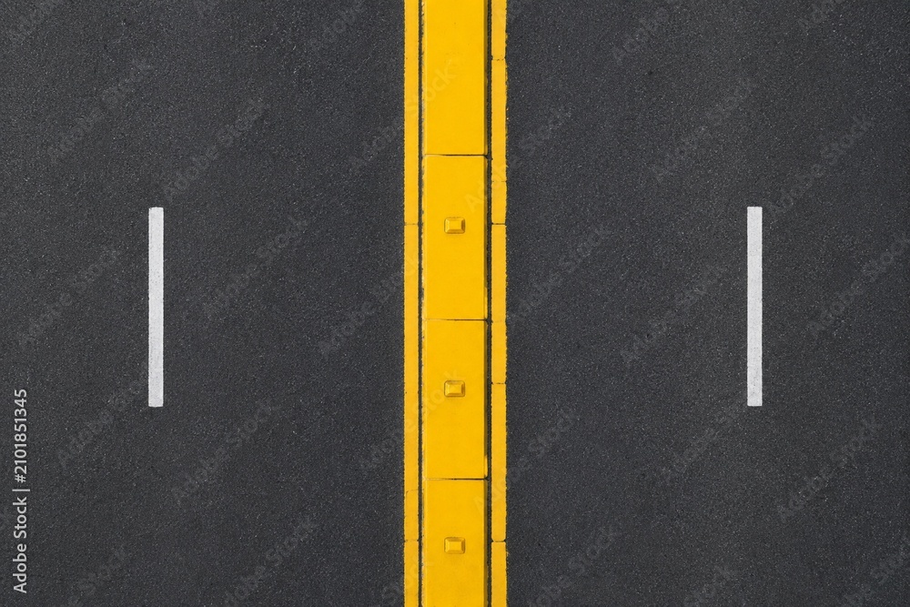 Fototapeta premium Top-down view of a yellow painted median strip dividing a two-lane road.