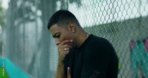 Foto Latin Hispanic man of African descent leaning against chain-link fence with hand