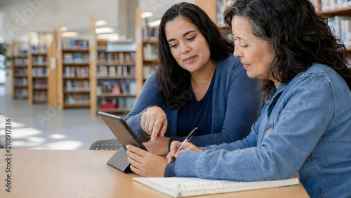 Adult Learner Practicing Digital Skills With Tutor in Library for International Literacy Day