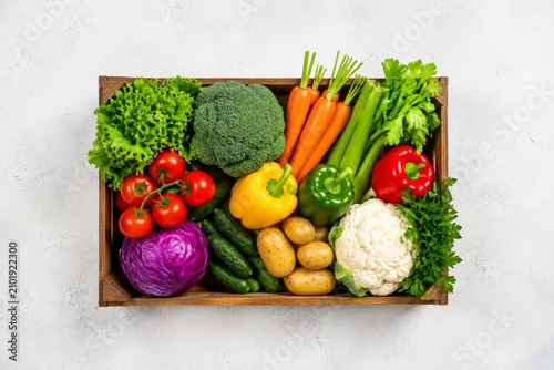 Obraz na plátne Crate with assorted fresh vegetables from top view on light background with clean composition