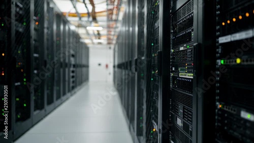 Side view of a commercial data center aisle showcasing rows of server racks in hot aisle configuration LED lights blinking distinctly while other equipment is softly blurred.