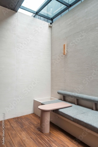 Modern Cafe Interior: A minimalist cafe interior features a comfortable built-in bench with soft cushions, a sleek pink side table, and warm wooden floors.