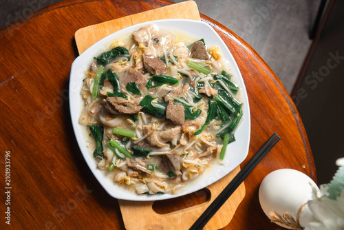 Canvastavla Savory Noodle Delight: A generous portion of stir-fried noodles, rich with tender meat, crisp vegetables, and a creamy sauce, served in a pristine white bowl, accompanied by chopsticks