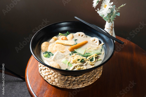 Foto Aromatic Noodle Soup Delight: A steaming bowl of savory noodle soup, brimming with fresh vegetables and tender ingredients, served with chopsticks, promises a comforting and delicious meal