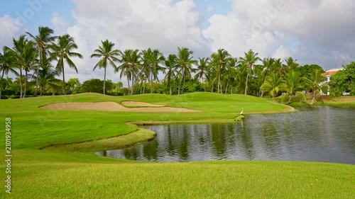 Panoramic view of a green golf course with a lake. Outdoor sports. Aerial view of a beautiful golf course with green grass and lakes in a park. Tranquil golf landscape.