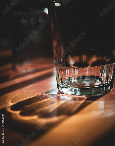 фотографія Empty drinking glass casting warm sunlight and shadows across a table