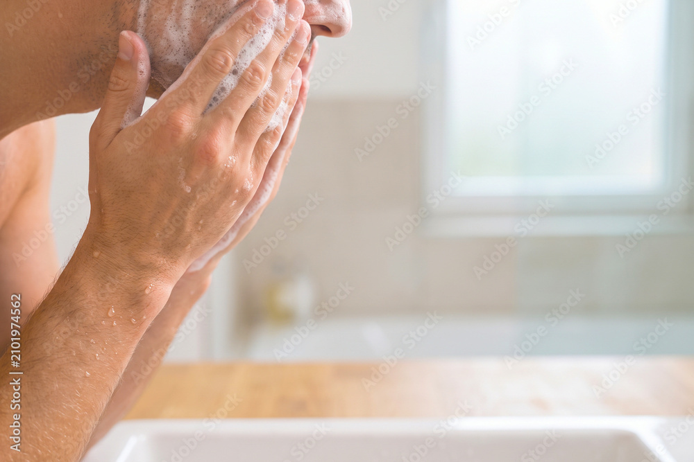 Fototapeta premium A man washing his face with soap and water in a clean bathroom