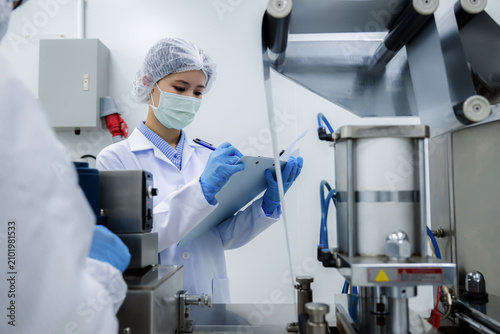 Photos Female quality control inspector holding clipboard checking automated manufacturing machinery
