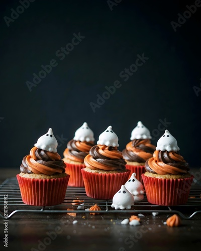 Festive halloween cupcakes with ghostly meringue toppings on a cooling rack perfect for parties