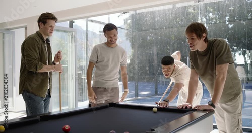 Diverse male friends playing pool at home, pointing to balls, lining up shots for fun