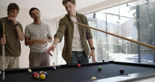 Men playing at pool table at home watching gesturing, shooter hitting cue ball, balls scattering