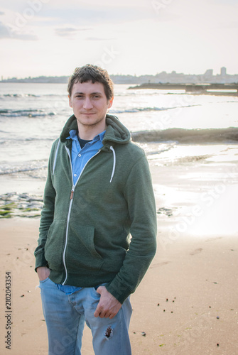 Young man standing on a beach at sunset, Estoril, Portugal
