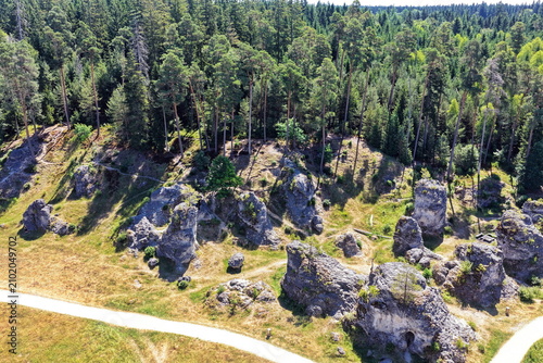 Luftaufnahme des Felsenmeers im Wental mit markanten Felsformationen aus Jurakalk, umgeben von einem dichten Nadelwald und Wanderwegen auf der Schwäbischen Alb bei Sonnenschein.
