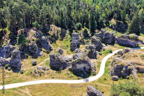 Luftaufnahme des Felsenmeers im Wental mit markanten Felsformationen aus Jurakalk, umgeben von einem dichten Nadelwald und Wanderwegen auf der Schwäbischen Alb bei Sonnenschein.