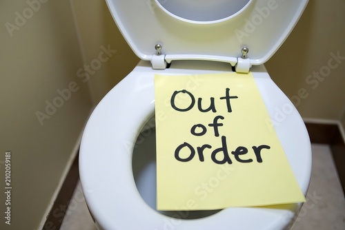 Handwritten Out of Order Sign on Paper Attached to Toilet Bowl in Bathroom