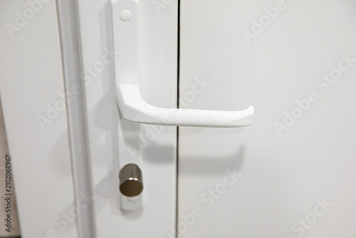 White plastic door with a handle and a lock with keys.