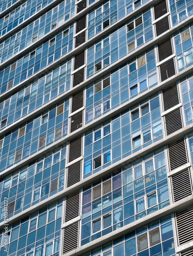Tall blue residential building with countless windows and modern urban architecture under bright daylight