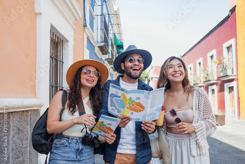 portrait of young latin friends traveling holding a tourist map in Mexico Latin America, hispanic people tourist in colonial city 
