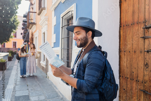 Latino man tourist or backpacker holding a touristic map in a traditional mexican colonial city in Mexico, Vacations at summer in latin america