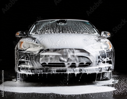 close up of car covered in soap foam washing in black background car wash service advertising concept