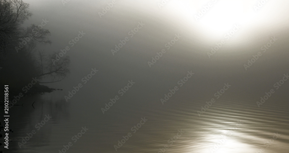Obraz premium Calm misty morning at a small lake covered in fog with transparent areas in the sky and on the water