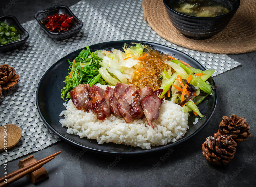 Fototapeta premium Roasted pork rice bowl with vegetables. Traditional Chinese BBQ pork served with steamed rice.