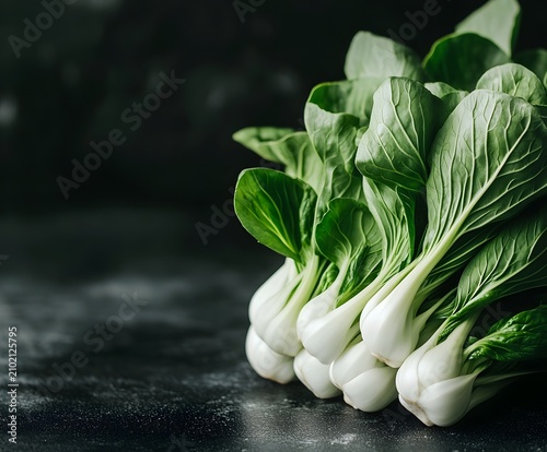Group of fresh bok choy vegetables laid out on dark textured surface with copyspace.