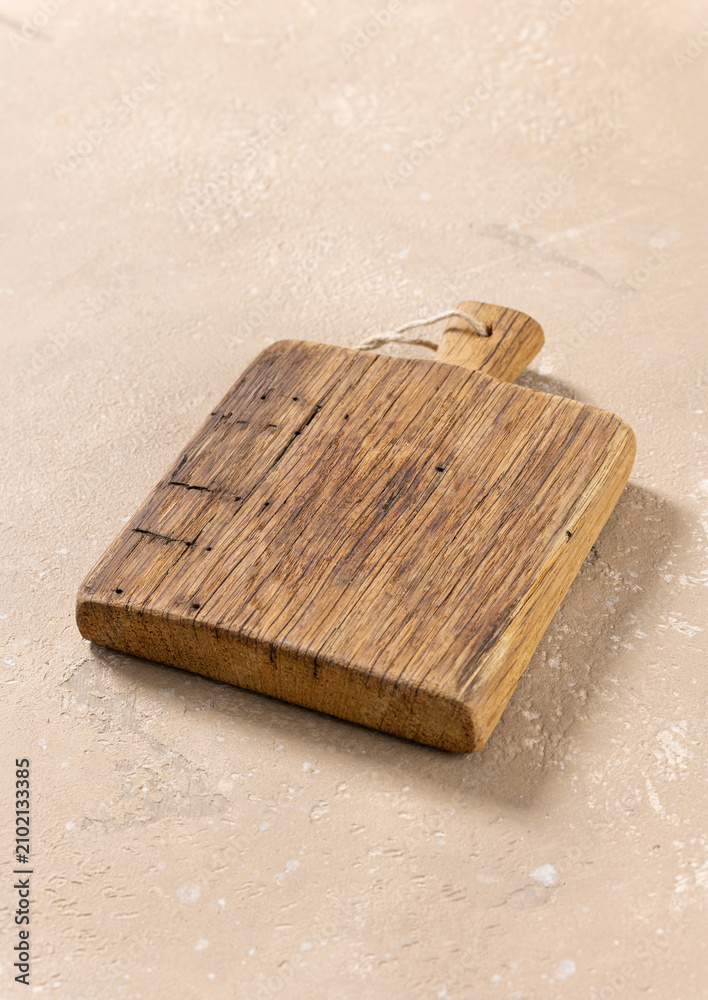 Obraz premium Empty Vintage Wooden Cutting Board on Beige Kitchen Table