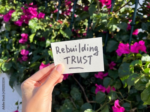 Rebuilding Trust - text in hand on pink flower background, relationship and forgiveness concept