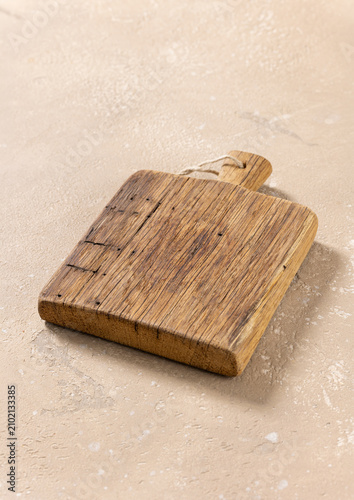 Foto Empty Vintage Wooden Cutting Board on Beige Kitchen Table