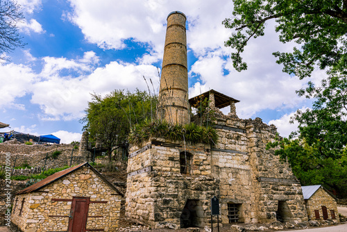 The historic limestone kiln and tall brick chimney stack standing under a cloudy sky at the entrance of the San Antonio Japanese Tea Garden.