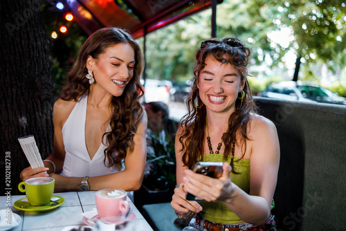 Friends enjoy drinks and share laughter in a cafe during a sunny afternoon