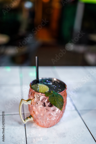 Fotografía Moscow mule in a copper mug on a table in a bar during evening hours