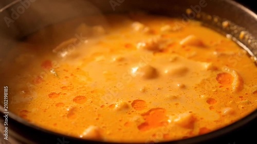 simmering orange curry stew with vegetables cooking in pot